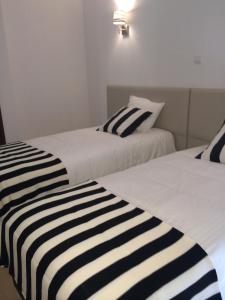 two beds with black and white striped sheets in a room at Nas Palhas Deitado in Fátima