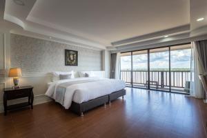 a bedroom with a large bed and a large window at Hotel de Ladda in Mukdahan
