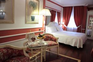 
a hotel room with a bed, chair, table and lamp at Palazzo Alabardieri in Naples
