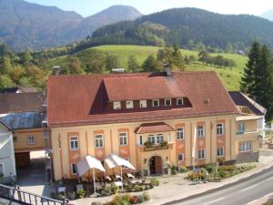 ein großes gelbes Gebäude mit braunem Dach in der Unterkunft Gästehaus zur Post - Heritage Inn in Spital am Pyhrn