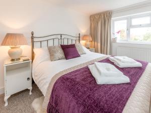 a bedroom with a large bed with a purple blanket at Walnut Cottage in Aldeburgh