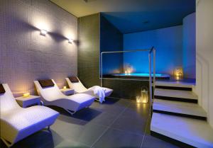 a lobby with white chairs and stairs with lights at DB Hotel Verona Airport And Congress in Caselle di Sommacampagna