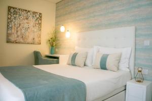 een slaapkamer met een wit bed en een schilderij aan de muur bij Batata - Ocean View in Nazaré
