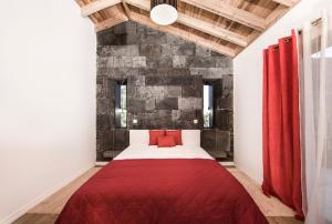 a bedroom with a red bed with a brick wall at Vila Verde in São Roque do Pico