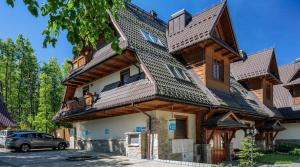 a large wooden house with a car parked in front at Rent like home - Tetmajera in Zakopane