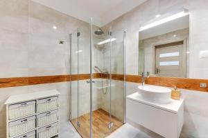 łazienka z przeszkloną kabiną prysznicową i umywalką w obiekcie Gdansk Comfort Apartments Bursztynowa w Gdańsku +27 zdjęć