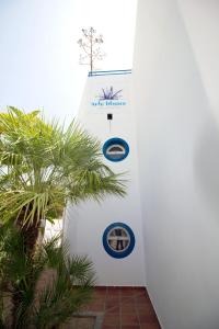 a white wall with logos on it next to a palm tree at Arto Blanco in Agua Amarga