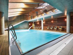 uma grande piscina num edifício com cadeiras em VacationClub - Sand Hotel Apartment 201 em Kolobrzeg
