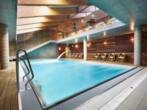 a large swimming pool in a building with chairs at VacationClub - Sand Hotel Apartment 201 in Kołobrzeg