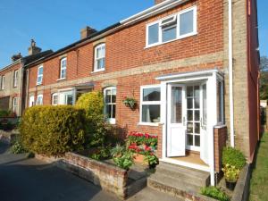 ein rotes Backsteinhaus mit einer weißen Tür und Blumen in der Unterkunft Walnut Cottage in Aldeburgh