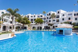 una piscina en un complejo con edificios blancos en Carema Garden Village, en Fornells