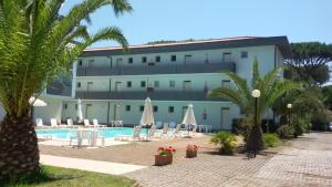 un hotel con piscina e palme di Residence Verde Pineta a Principina a Mare