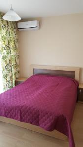 バルチクにあるBalchik Gardens Apartmentsの紫色のベッドカバーが備わる客室です。
