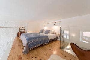 ein weißes Schlafzimmer mit einem Bett und einer Glaswand in der Unterkunft LovelyStay - Cativo Mezzanine Studio in Porto