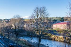 a river with cars parked on the side of it at Riverside View Apartment in Hawick