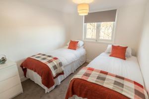 two beds in a small room with a window at Riverside View Apartment in Hawick