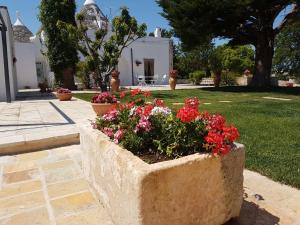 a stone planter with red flowers in a yard at Trulli Dal Conte in Locorotondo