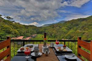 a table on a balcony with a view of a mountain at The Rainforest Ecolodge - Sinharaja in Deniyaya