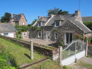 an old stone house with a white fence at Au Clair de la Dune in Frehel