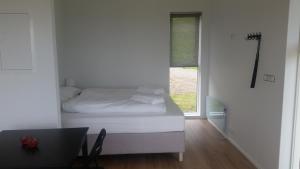 a white bedroom with a bed and a window at Krákhamar Apartments in Djúpivogur