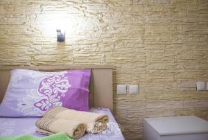 1 dormitorio con 1 cama con almohadas moradas y blancas en Villa Alexander, en Vrasná