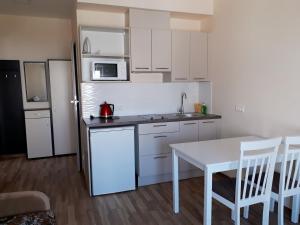 a kitchen with white cabinets and a white table and chairs at Laimos vila in Palanga