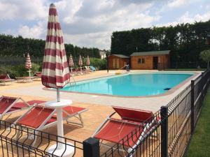 - une piscine avec 2 chaises et un parasol dans l'établissement Agriturismo Pigno, à Villafranca di Verona