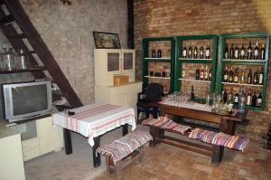 a room with a table and a television and bottles of wine at Guest House Stara Baranja in Kneževi Vinogradi