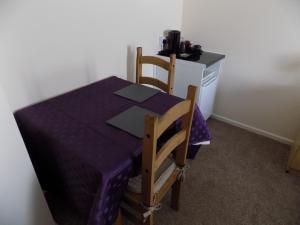 普里茅斯的住宿－A Home From Home 2，一张桌子,一张桌子,上面有紫色的桌布和两把椅子