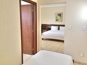 a bedroom with a bed and a door leading into a room at Hotel Mohallem in Passos