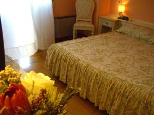 ein Schlafzimmer mit einem Bett, einem Stuhl und Blumen in der Unterkunft Macallè in Momo