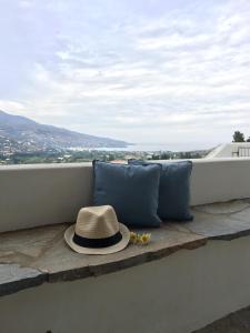 un sombrero sentado en una cornisa con almohadas en Villa Sis, en Aïdhónia