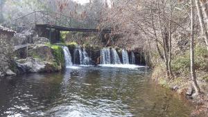 a bridge over a river with a waterfall at Casas dos Carregais in Carregais