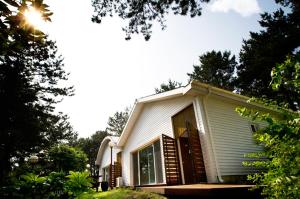 a small white house with the sun shining on it at RnB Town Pension in Seogwipo