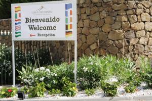 a sign in front of a stone wall with flowers at Colina del Paraiso in Estepona