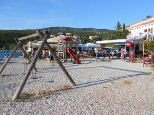 a playground with a swing set on a beach at Apartment Tušek in Jadranovo