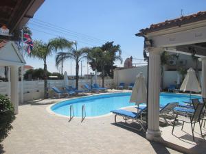 a swimming pool with chairs and umbrellas next to a building at Tsialis Hotel Apartments in Larnaka