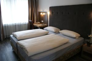 a bedroom with two beds with white pillows at Bahn-Hotel in Düsseldorf