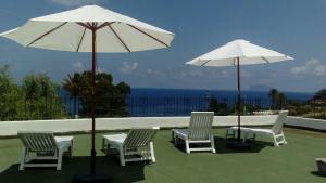 eine Gruppe von Stühlen und Sonnenschirmen auf einer Terrasse in der Unterkunft Case Vacanze Villa Lory in Malfa