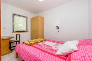 a bedroom with a bed with a pink checkered blanket at Apartments Nevenka in Krk