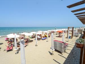a beach with umbrellas and chairs and people on the beach at Gelso Bianco Apartments in Campofelice di Roccella