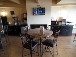a dining room table with chairs and a tv on the wall at Super 8 by Wyndham Beaver Falls in Beaver Falls