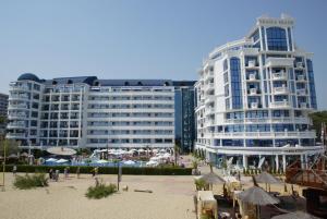 two tall buildings with umbrellas in front of a beach at Chaika Beach Resort in Sunny Beach