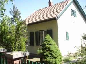 une petite maison blanche avec un arbre en face dans l'établissement Oázis Vendégház, à Gyula