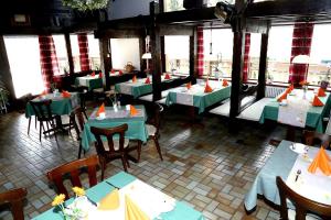 a restaurant with green tables and chairs and windows at Landhotel Garni Schweizerhaus in Schönwald