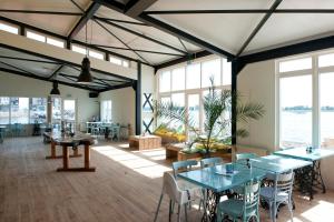 a large room with tables and chairs and windows at Camping Marina Eemhof in Zeewolde