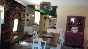 uma cozinha com uma mesa de madeira e cadeiras brancas em Casa Bernaldo em Covas do Monte