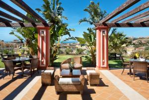 patio ze stołami, krzesłami i pergolą w obiekcie Colina del Paraiso w mieście Estepona