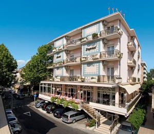 a large building with cars parked in a parking lot at Hotel Saponi in Rimini