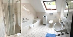 a bathroom with a tub and a toilet and a sink at Lokal Genial Pension & Restaurant in Beelitz